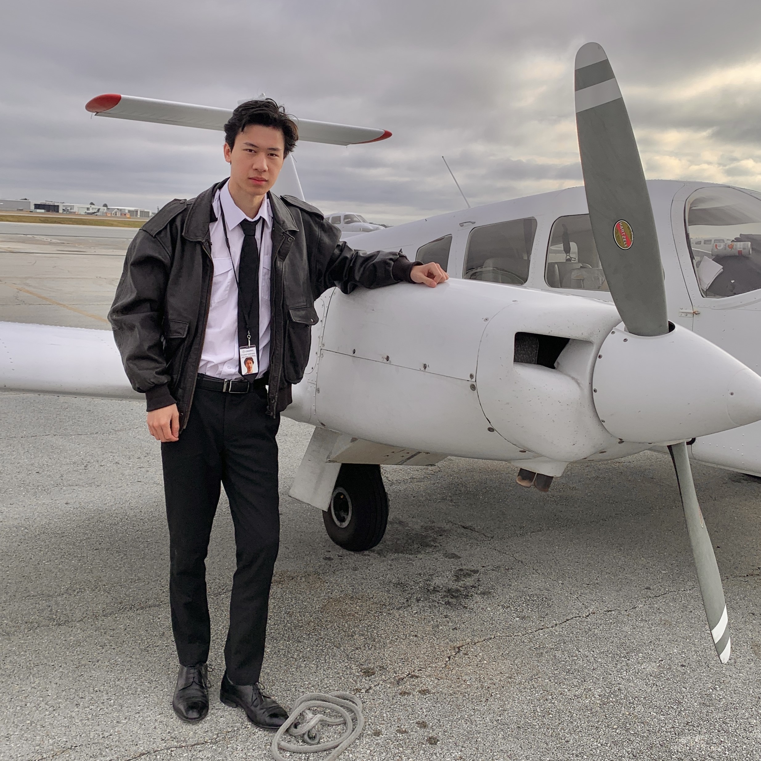Jake Wong in pilot attire beside a twin-engine aircraft on the apron.